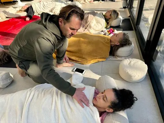 Bart at the center of a group of people, guiding them through a somatic healing session.
